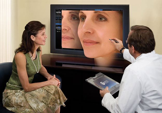 Woman Looking at Vectra Image of Her Face with Surgeon Pointing out Details