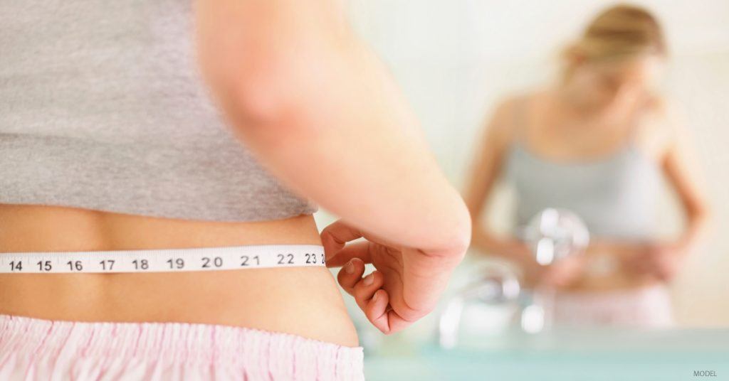 Woman measures waist with tape measure