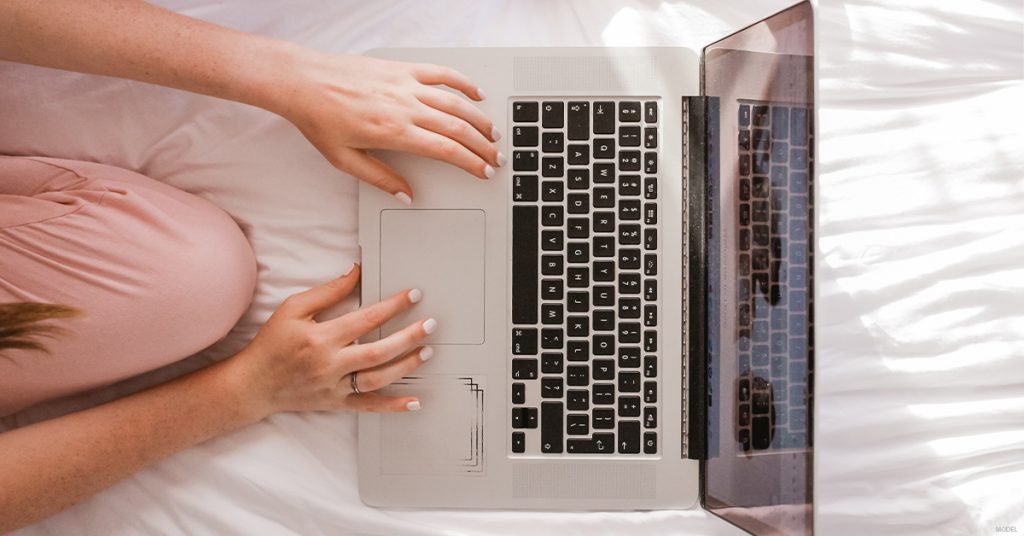 Bird's eye view of woman's hands typing on laptop keyboard