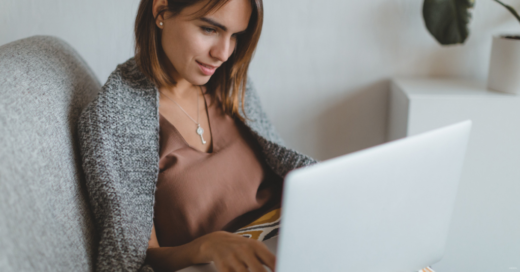 A woman in Staten Island looks at laptop to research the benefits of breast augmentation and a breast lift.