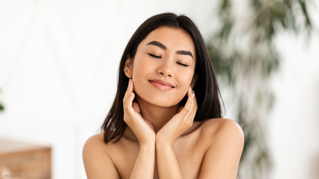 Model smiling and holding face with hands.