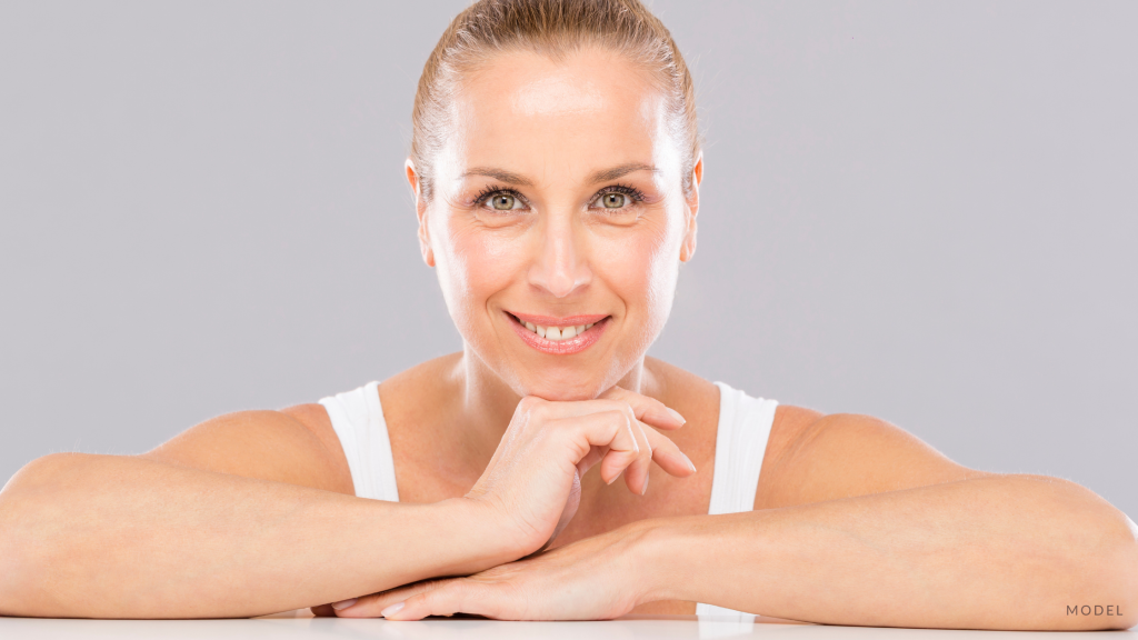 Woman with arms crossed and hand on face. (MODEL)