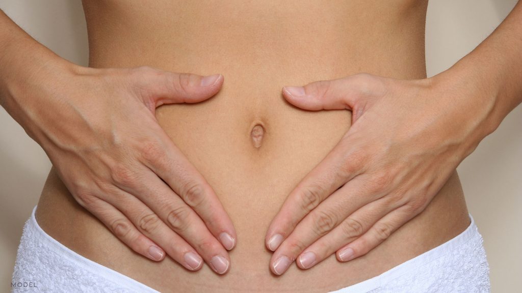 Woman with her hands on her stomach. (MODEL)