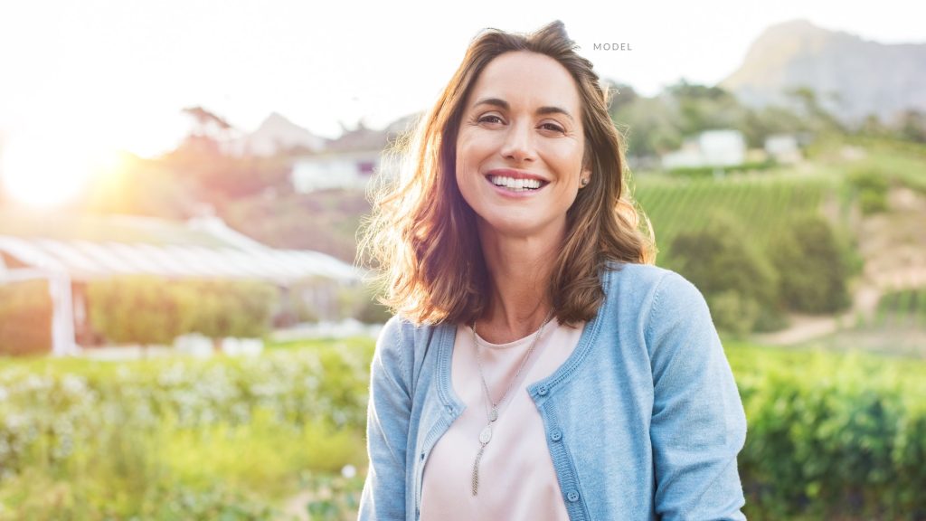 Female (model) looks into the camera while the sun sets behind her