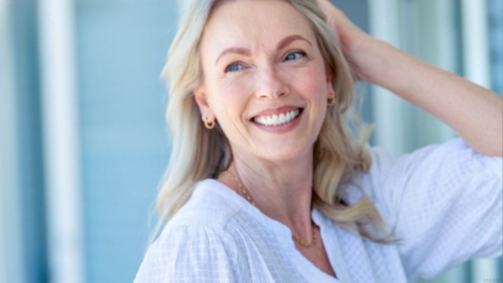 Mature woman smiling with her hands on her head (model)